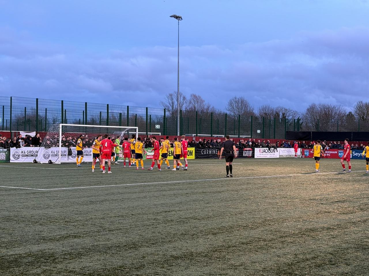 A floodlight tower against the evening sky during a match at the Elmbridge Xcel Sports Hub