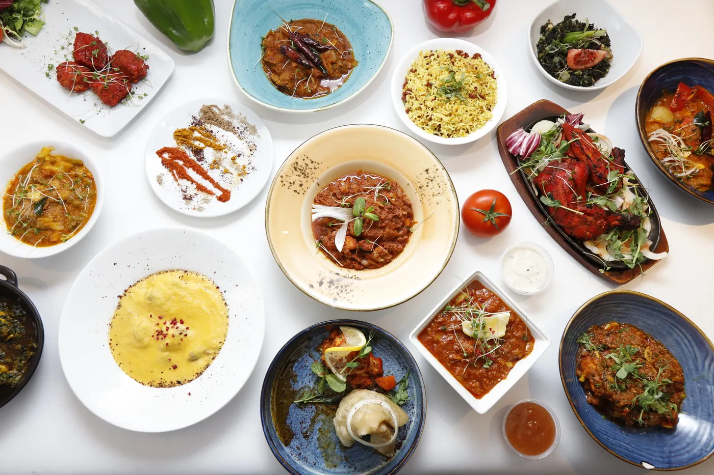An overhead spread of Khyber Pass dishes, including curries, tandoori chicken, rice and side dishes