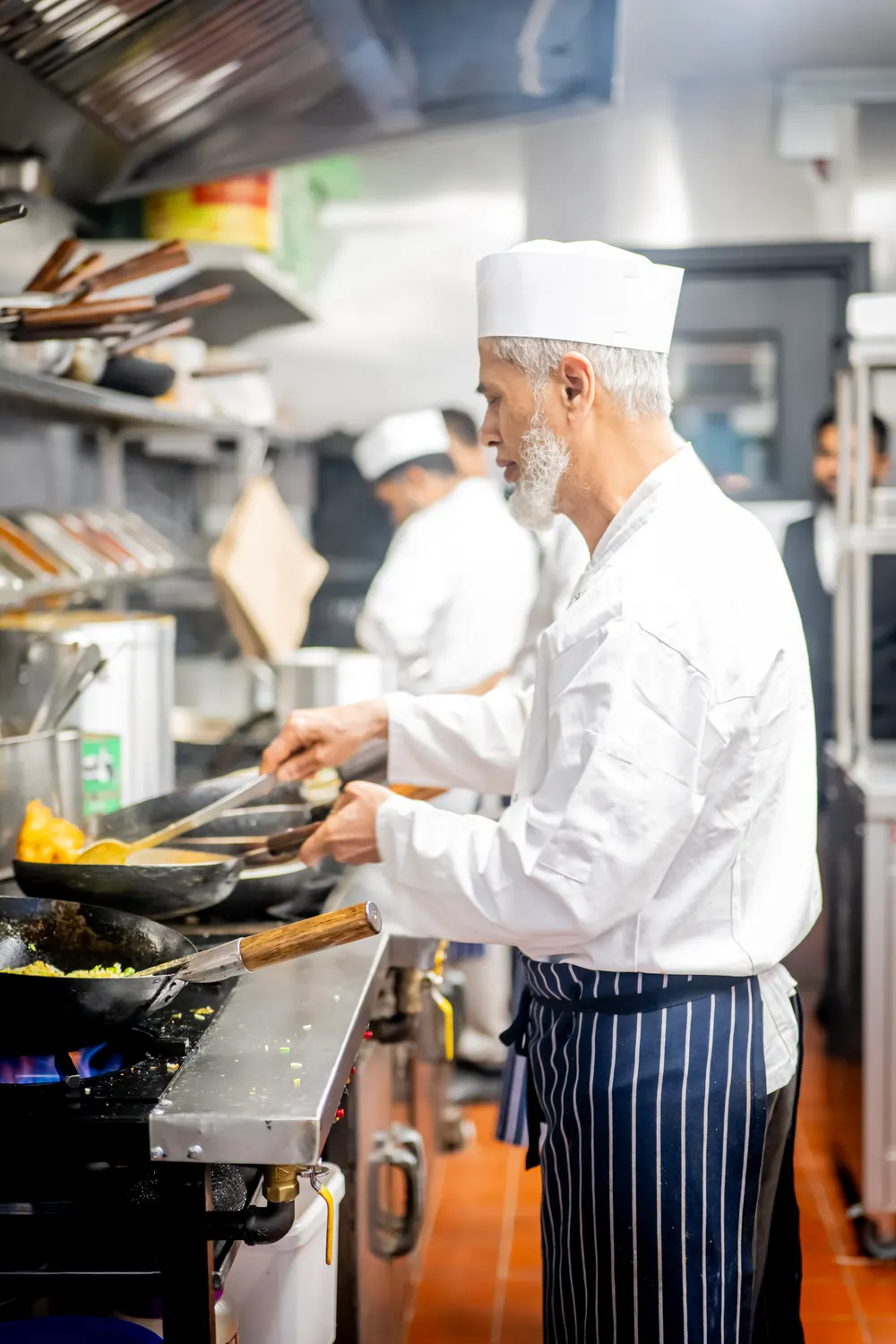 A chef preparing dishes at the range in the Khyber Pass kitchen