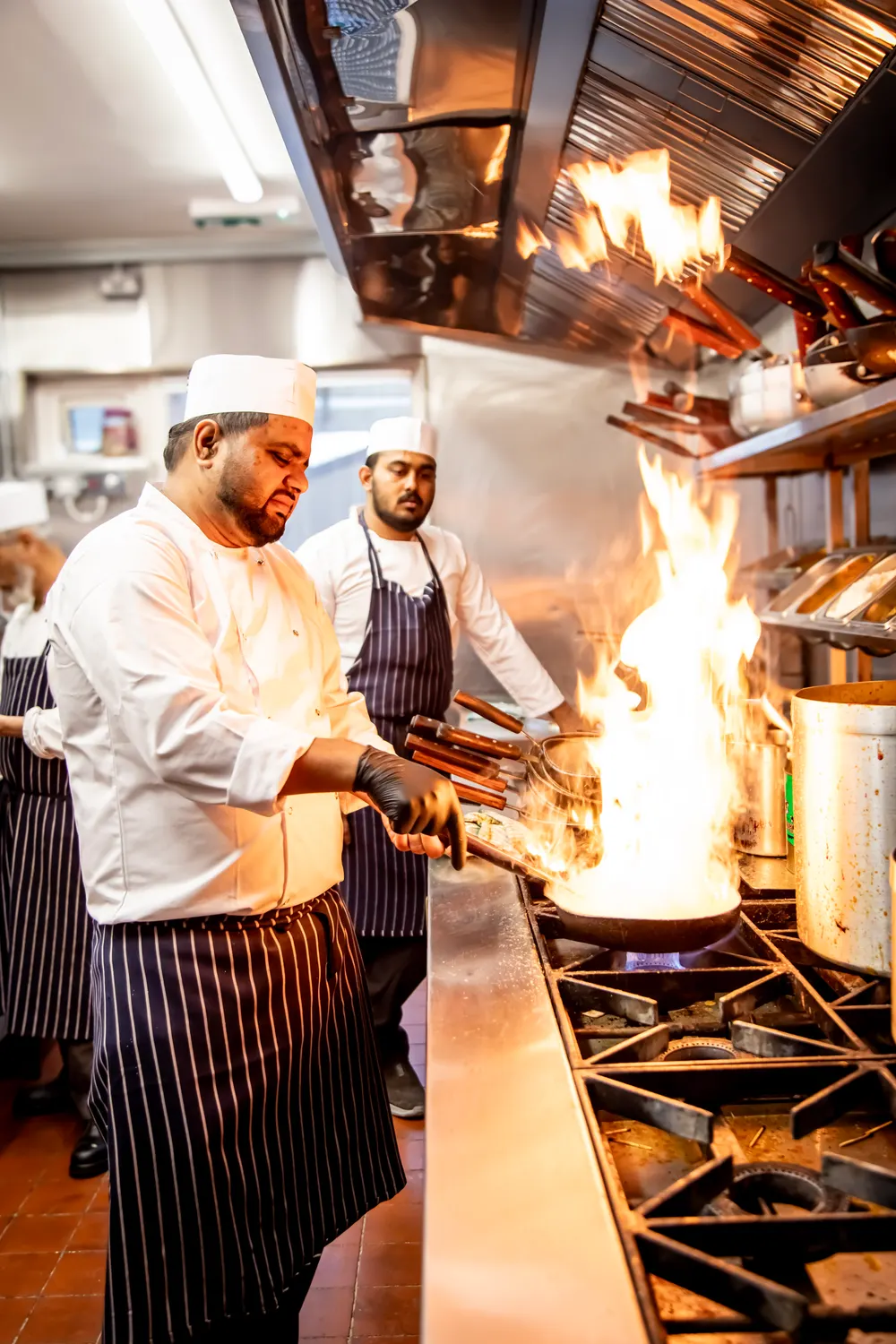 A chef cooking over open flames at the range in the Khyber Pass kitchen