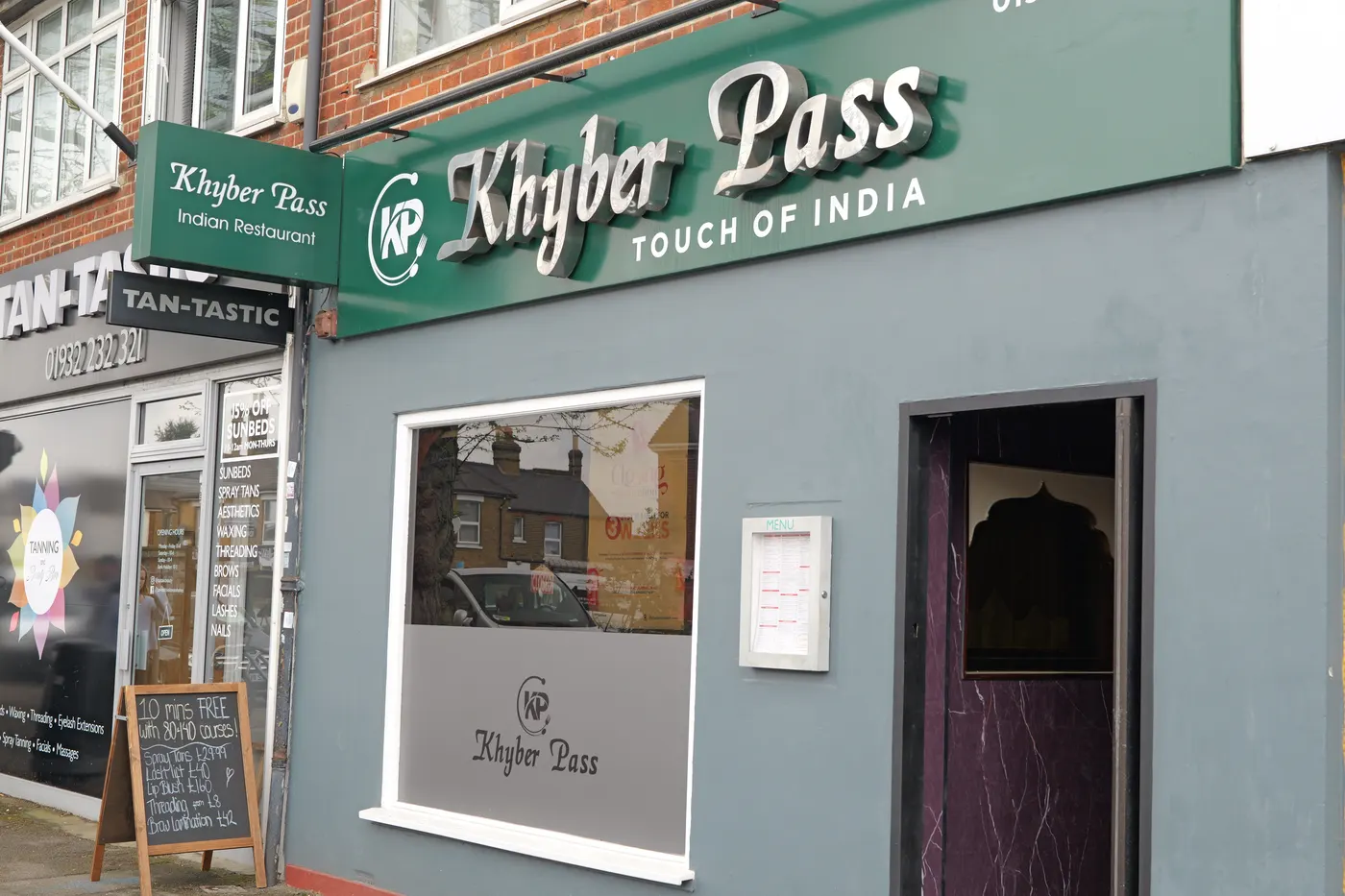 The grey and green shopfront of Khyber Pass at 54 Terrace Road, Walton-on-Thames, with its Touch of India fascia and a menu case beside the door