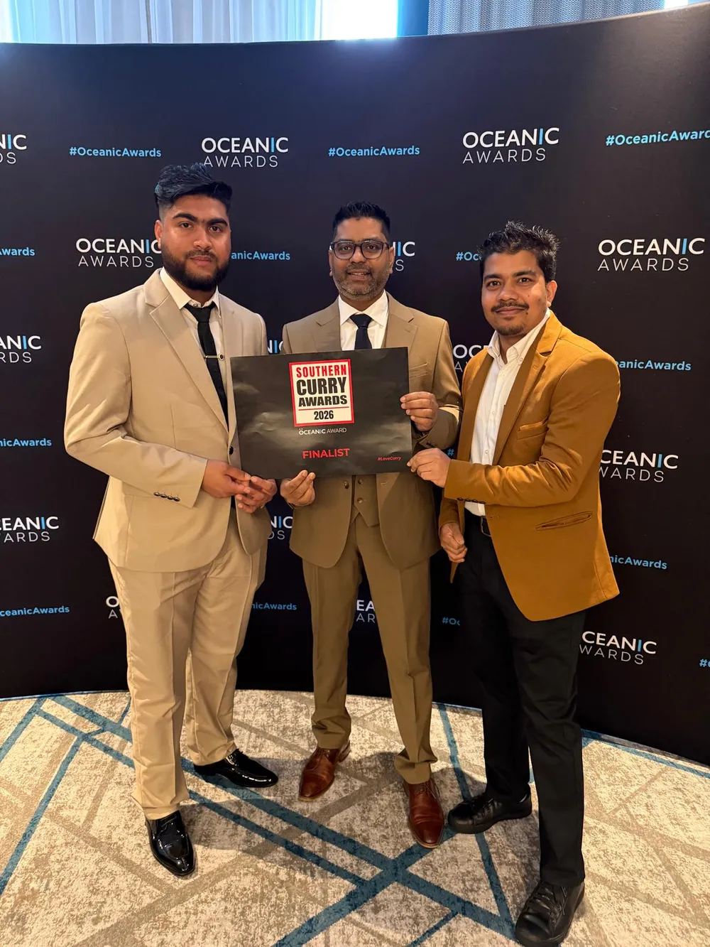Three members of the Khyber Pass team holding their Southern Curry Awards 2026 certificate at the awards ceremony