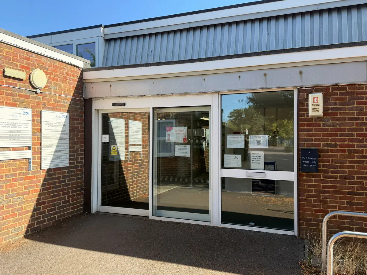 The main entrance to Walton Health Centre: glazed doors in a brick and white-panelled front, with NHS notice boards on the wall to the left