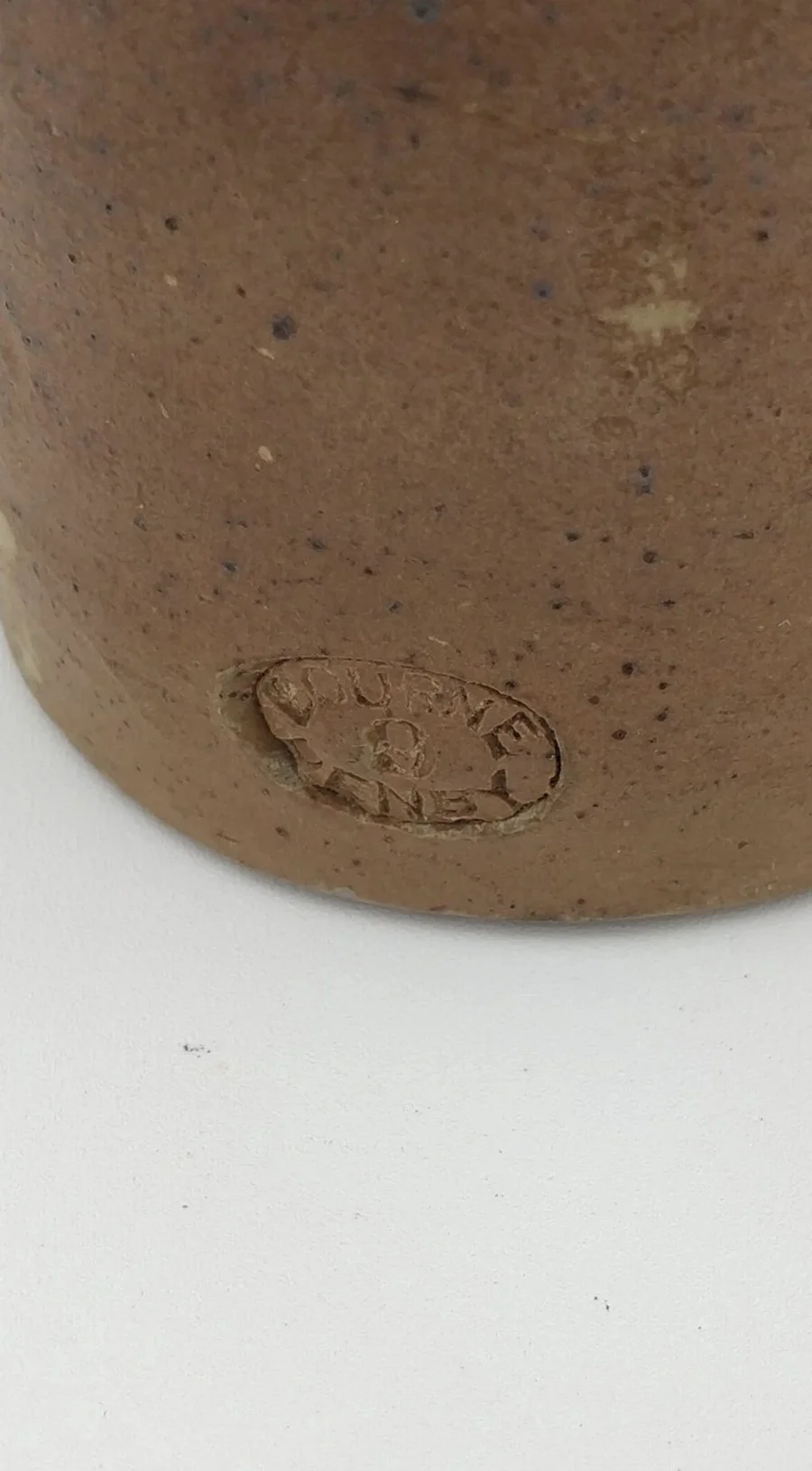 A worn oval maker's stamp on the base of the stoneware Savage & Son bottle