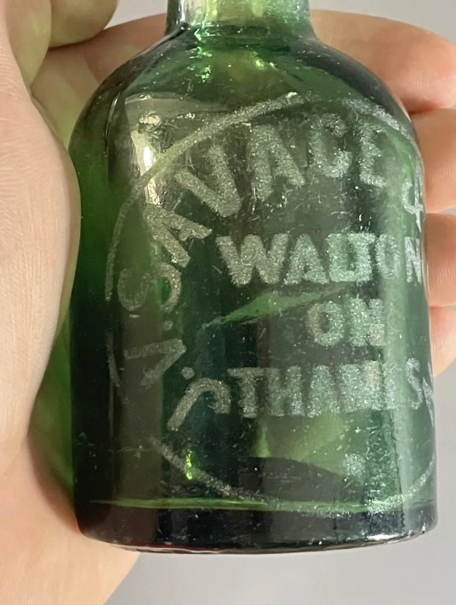 Close view of the embossed lettering on the green Savage & Son bottle