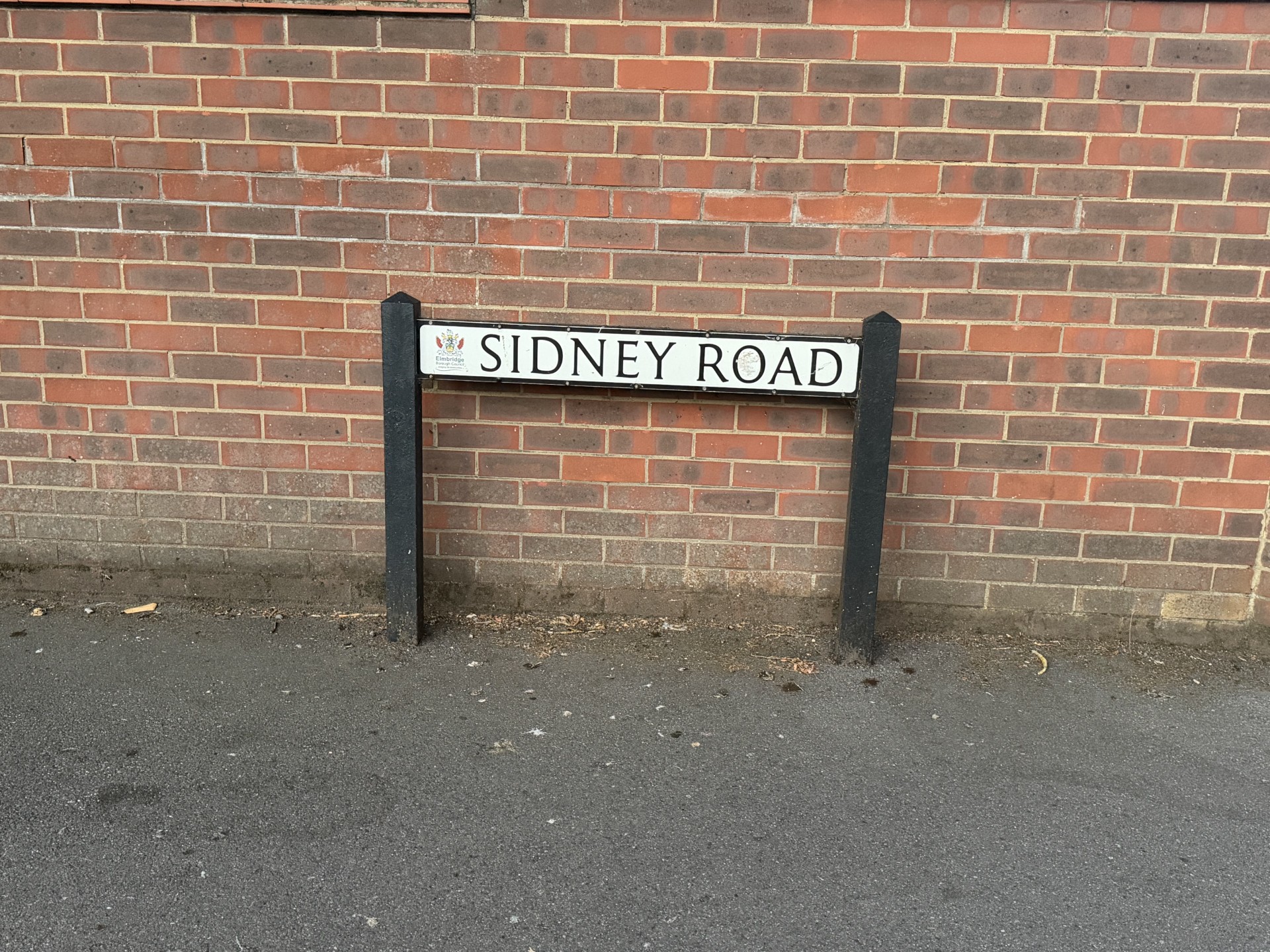The Sidney Road street sign, Walton-on-Thames, mounted on a brick wall