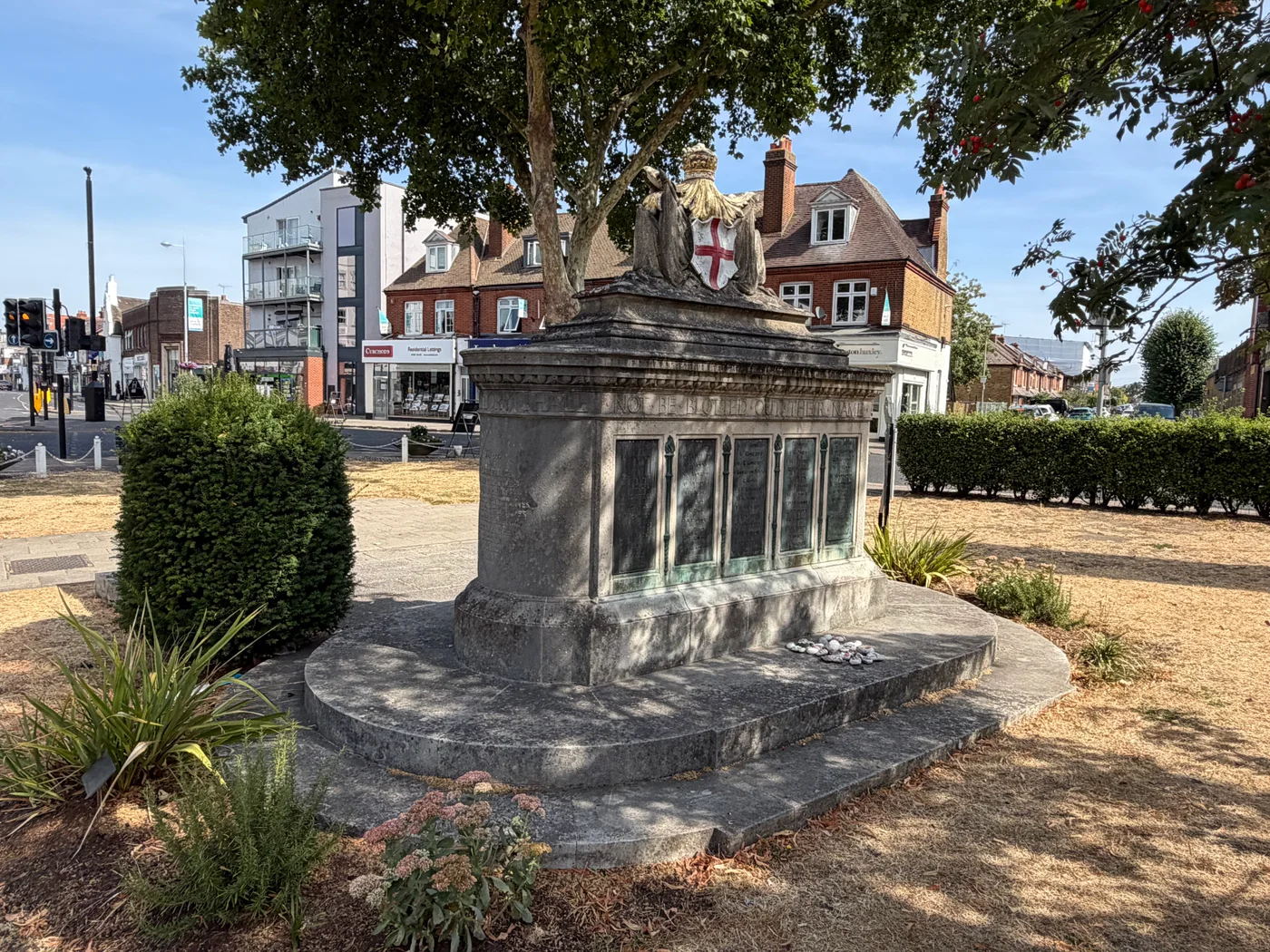 Rear three-quarter view of the Walton-on-Thames War Memorial with bronze panels, stepped base and a crowned St George's Cross emblem