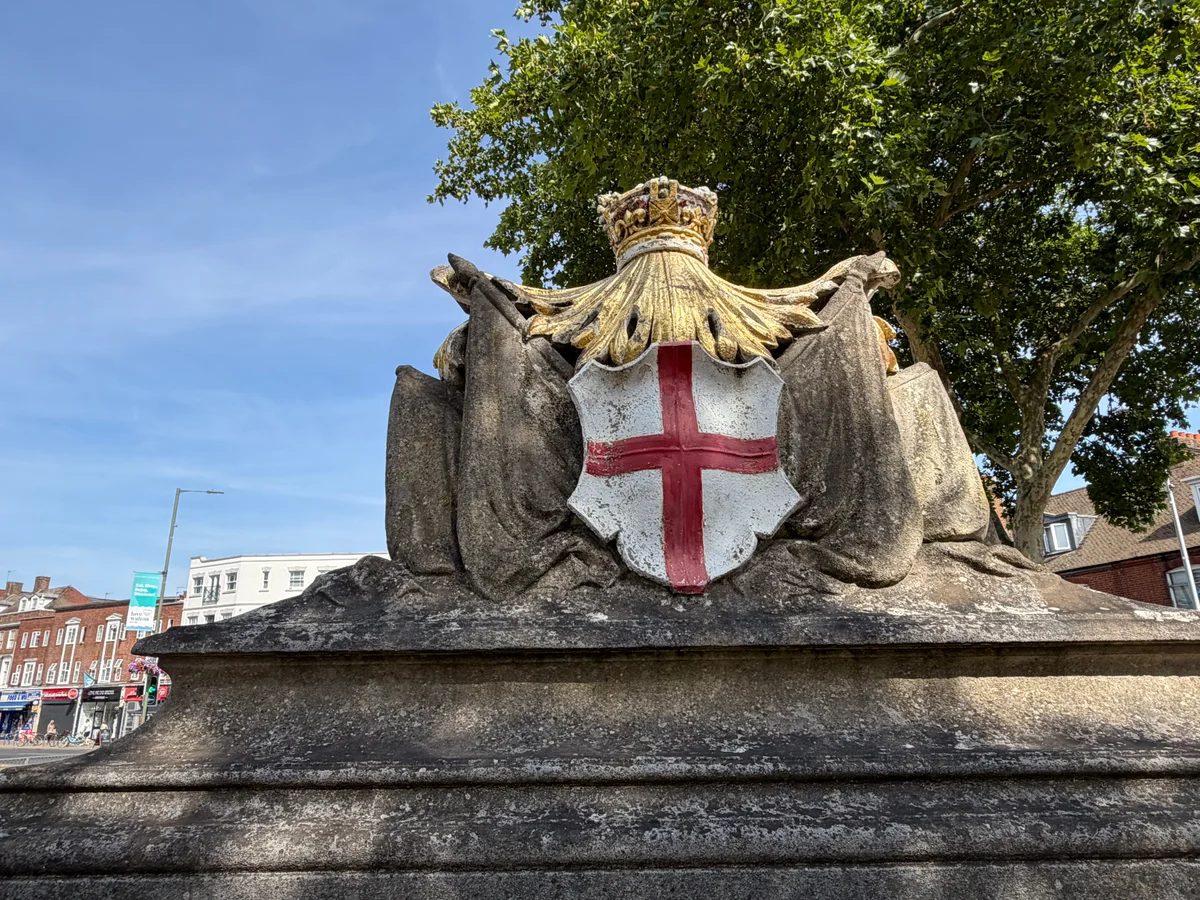 Close-up of the crowned St George's Cross shield and draped stone flags on the rear of the Walton-on-Thames War Memorial